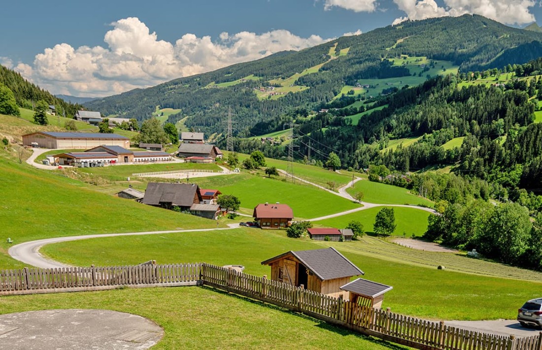 Blick vom Hotelzimmer in die Landschaft mit gr&uuml;nen H&uuml;geln, Bauernh&ouml;fen und bewaldeten Bergen im Hintergrund mit der Planai in Schladming