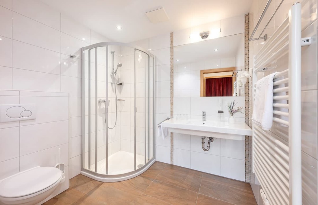 Modernes Badezimmer mit ebenerdiger Dusche, Waschbecken und Toilette in hellen Farben