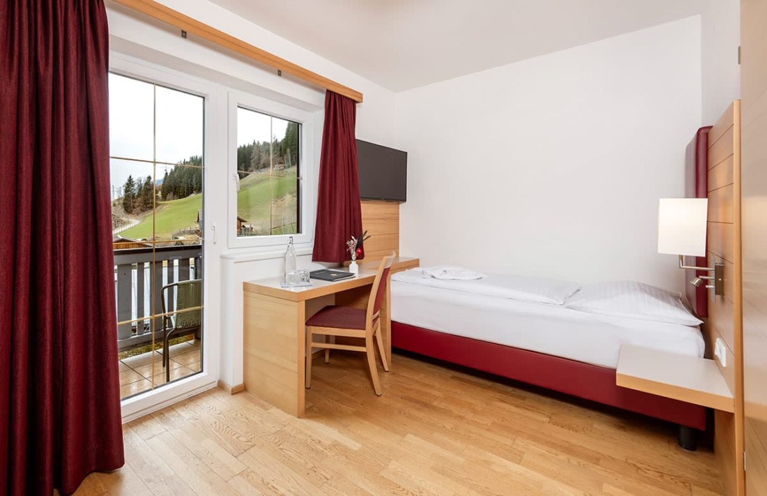 Helles Hotelzimmer mit Einzelbett und Balkonblick im Hotel Sonnschupfer