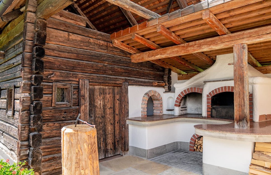 Grillh&uuml;tte mit &uuml;berdachtem Backofenbereich und gestapeltem Holz