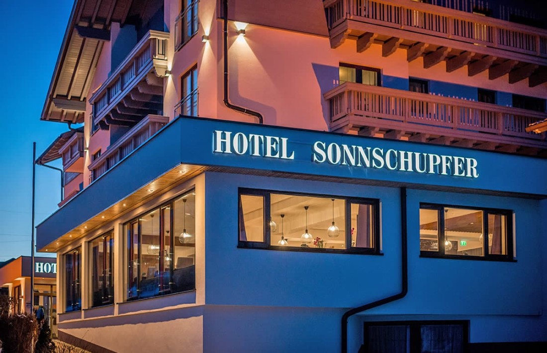 Hotelgeb&auml;ude Sonnschupfer bei D&auml;mmerung mit beleuchtetem Schriftzug