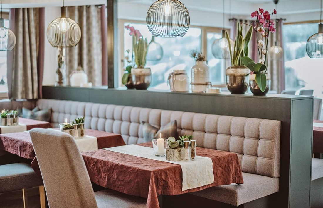 Gem&uuml;tliches Restaurantinterieur mit Tischen, Sofas und dekorativen Pflanzen in warmem Licht