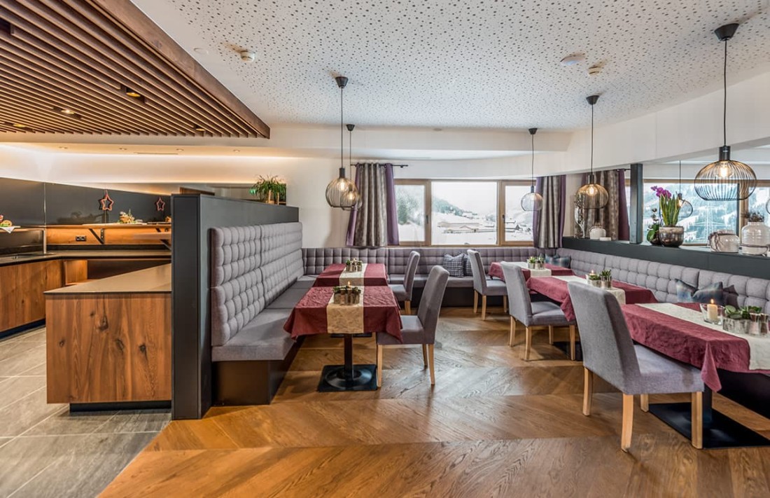 Moderner Speisebereich mit grauen Sitzb&auml;nken und rot gedeckten Tischen