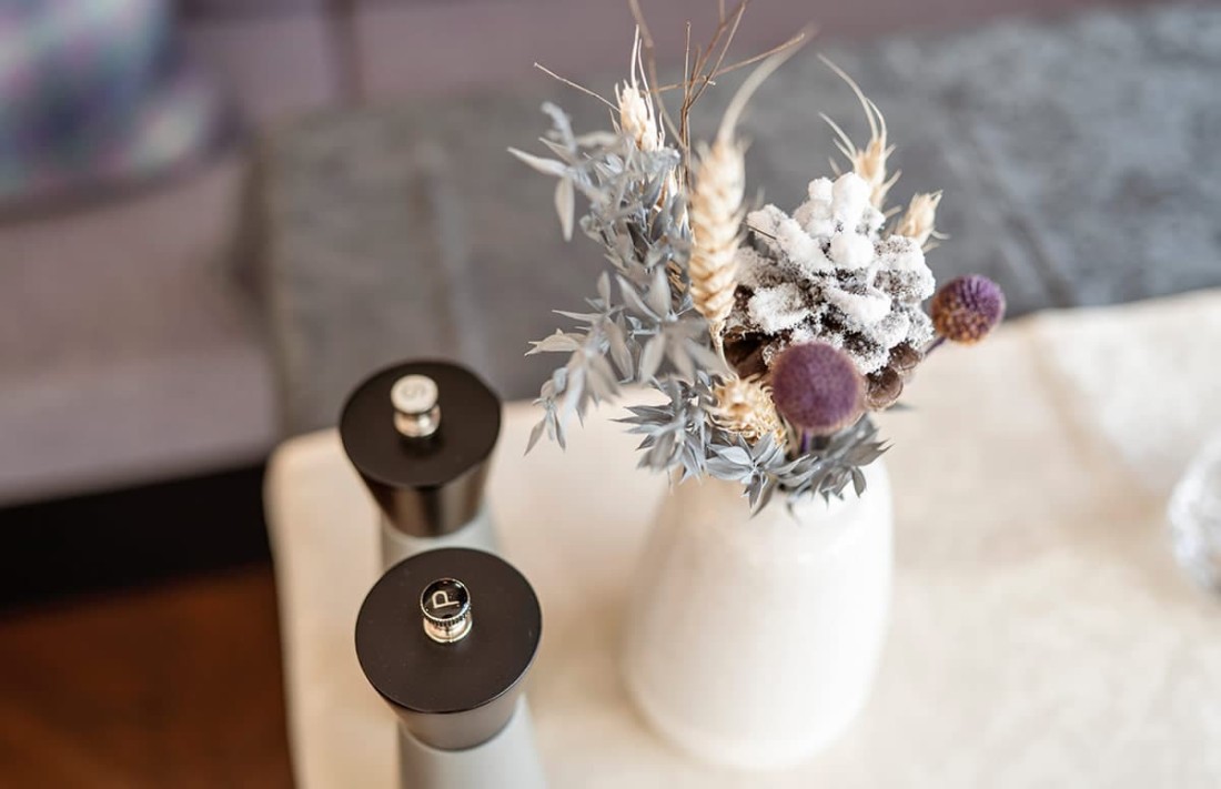 Vase mit getrockneten Blumen und Tannenzapfen, daneben Pfeffer- und Salzstreuer