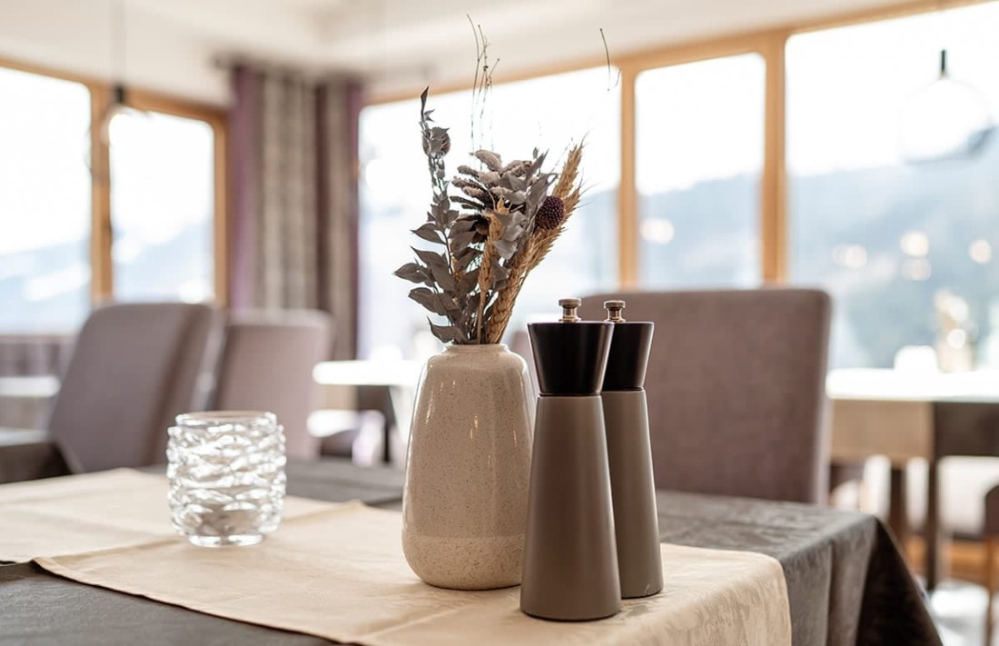 Vase mit Trockenblumen und Pfefferstreuer auf einem gedeckten Tisch