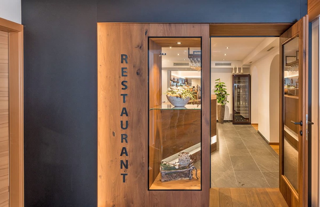 Eingang zu einem eleganten Restaurant mit Holzt&uuml;ren und moderner Beleuchtung