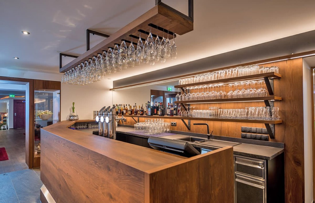 Moderne Bar mit Holztheke, Gl&auml;sern und Spirituosen im Hintergrund