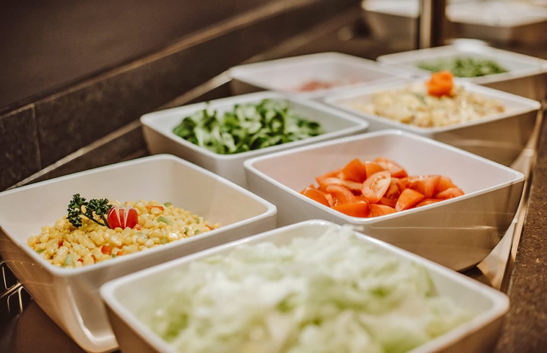 Mehrere Sch&uuml;sseln mit frischem Salat und Gem&uuml;se stehen nebeneinander