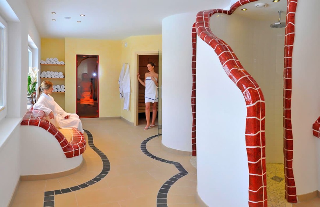 Zwei Frauen entspannen in einem stilvoll gefliesten Spa-Bereich mit Handt&uuml;chern an der Wand